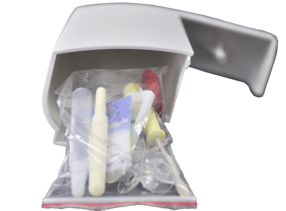 Na zdjęciu widoczny jest biały pojemnik z otwartą pokrywą, z którego wystają różne akcesoria do szycia, takie jak igły, nici i plastikowe elementy. Akcesoria są zapakowane w przezroczystą plastikową torebkę.