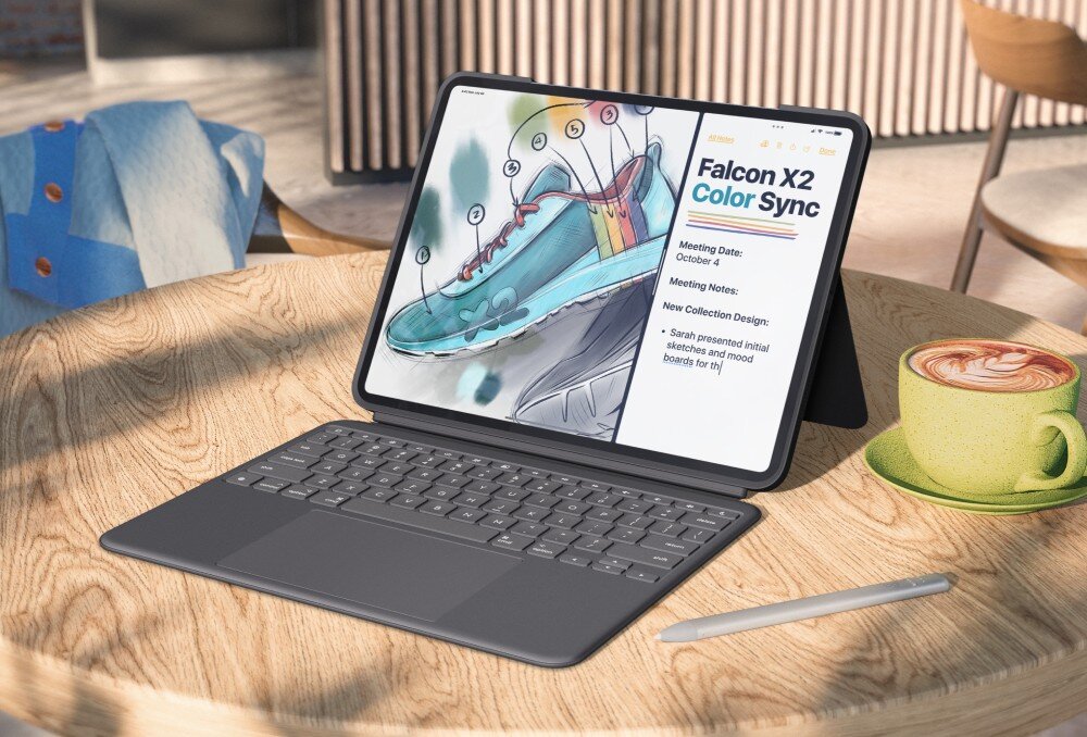 Na drewnianym stole znajduje się iPad w etui z klawiaturą, wyświetlający ilustrację buta i tekst \'Falcon X2 Color Sync\'. Obok leży rysik i filiżanka kawy na spodku.