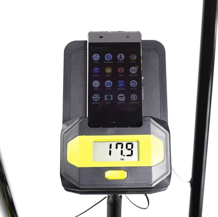 Na zdjęciu widoczny jest wyświetlacz urządzenia z wartością 179 CAL oraz smartfon z ikonami aplikacji na ekranie. Urządzenie ma czarno-żółtą obudowę.