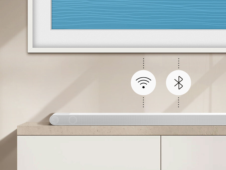 Biały soundbar umieszczony na jasnym blacie, nad nim widoczne są ikony Wi-Fi i Bluetooth. W tle znajduje się fragment obrazu z niebieskim wzorem przypominającym fale.