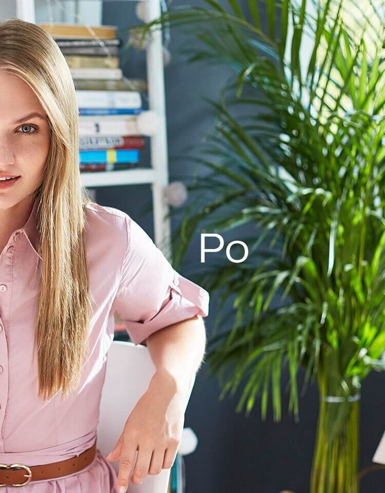 Osoba w różowej koszuli siedzi na krześle, obok znajduje się zielona roślina. Na obrazie widoczny jest tekst: \'Po\'.