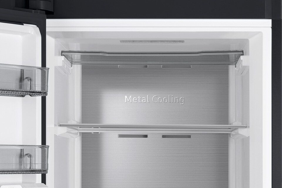 Wnętrze zamrażarki z półkami i napisem \'Metal Cooling\' na tylnej ścianie. W drzwiach znajdują się przezroczyste pojemniki.