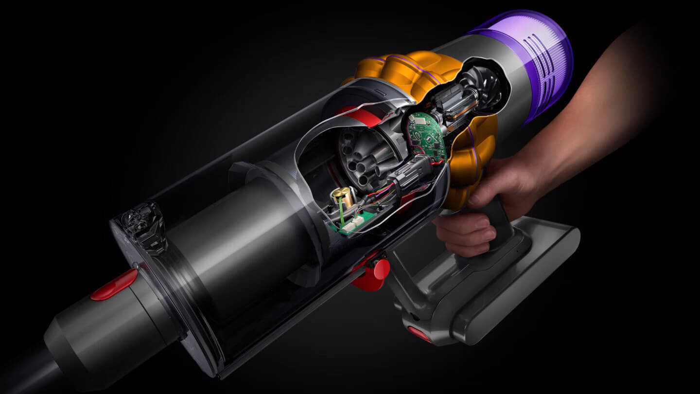 Obraz przedstawia wnętrze odkurzacza z widocznymi elementami elektronicznymi i mechanicznymi. Urządzenie trzymane jest w dłoni, a jego obudowa jest częściowo przezroczysta, ukazując wewnętrzne komponenty.