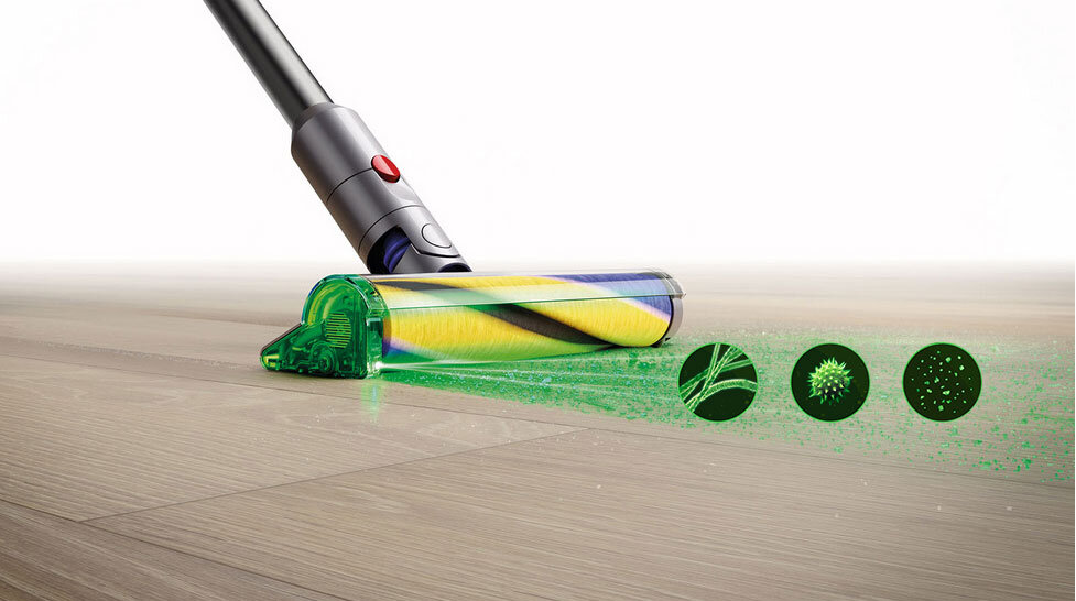 Obraz przedstawia odkurzacz z przezroczystą końcówką, która emituje zielone światło na podłogę. Obok widoczne są trzy zielone okręgi z różnymi wzorami, symbolizujące różne rodzaje zanieczyszczeń.