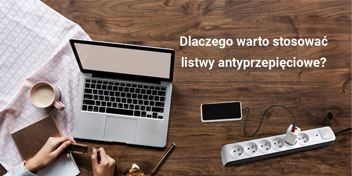 Na drewnianym stole znajduje się otwarty laptop, filiżanka z napojem, telefon oraz listwa zasilająca z podłączonym urządzeniem. Tekst na obrazie brzmi: \'Dlaczego warto stosować listwy antyprzepięciowe?\'.