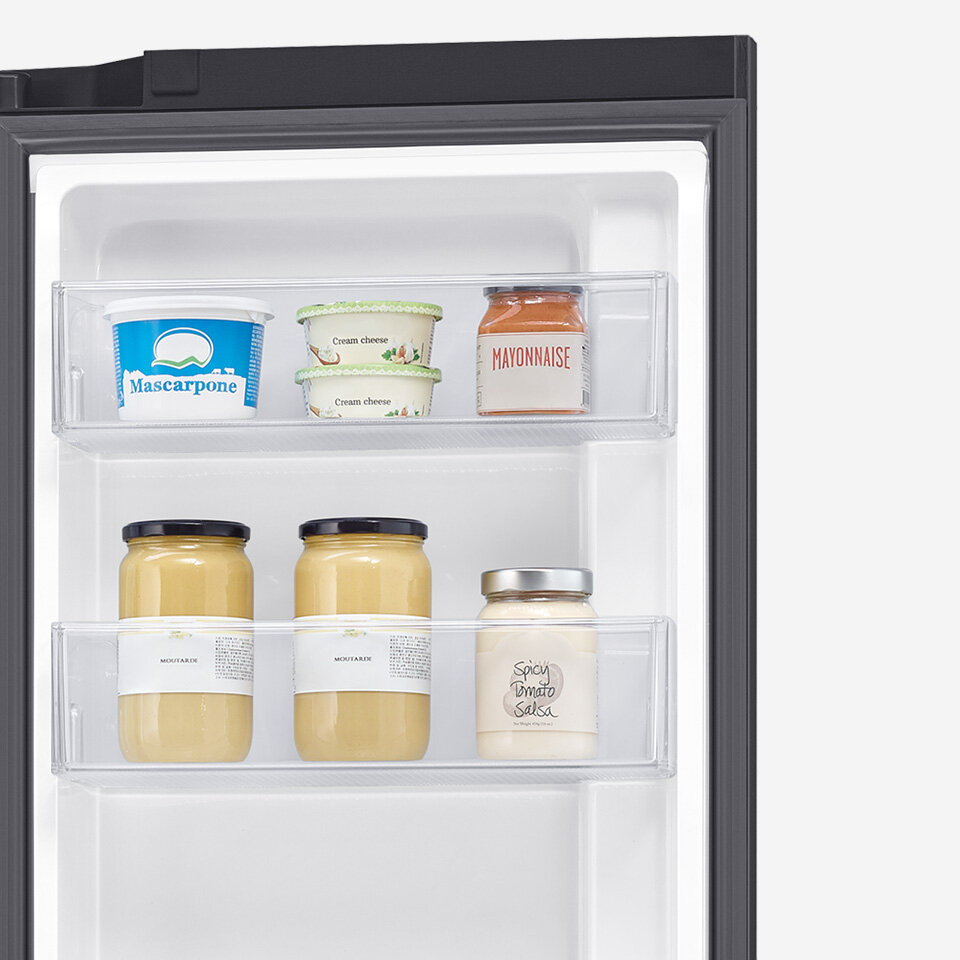 Wnętrze lodówki z dwoma półkami na drzwiach, na których znajdują się różne produkty spożywcze. Widoczne są opakowania z napisami: \'Mascarpone\', \'Cream cheese\', \'MAYONNAISE\', \'MOUTARDE\' i \'Spicy Dinner Salsa\'.