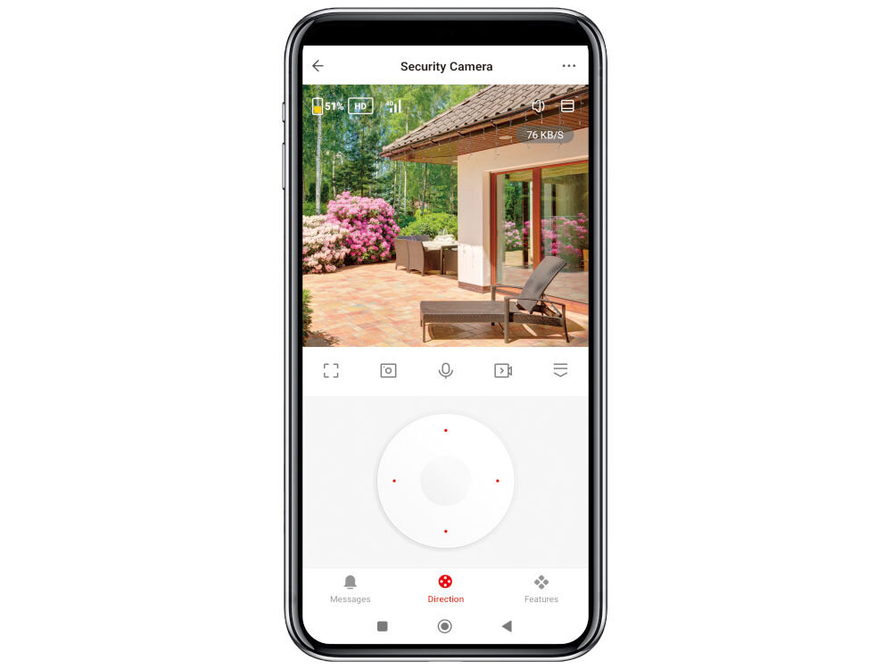 Na ekranie smartfona widoczny jest interfejs aplikacji do obsługi kamery bezpieczeństwa, pokazujący obraz zewnętrznego tarasu z roślinami i meblami ogrodowymi. Na górze ekranu znajdują się ikony statusu, a na dole przyciski nawigacyjne, w tym \'Messages\', \'Direction\' i \'Features\'.