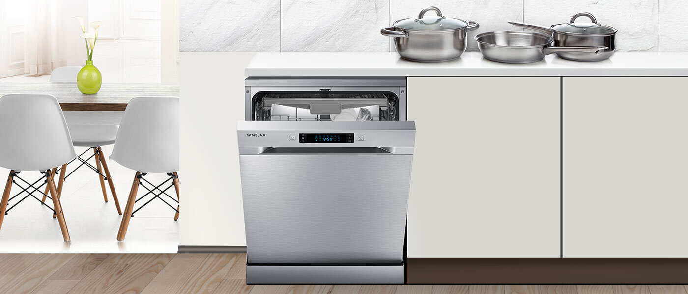 Zmywarka SAMSUNG w zabudowie kuchennej z otwartymi drzwiami, na blacie stoją garnki. Obok znajduje się stół z białymi krzesłami.