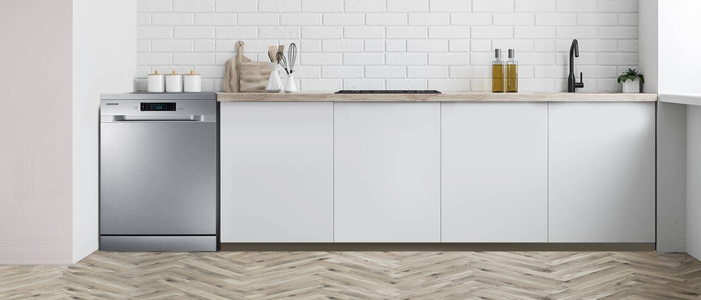 Kuchnia z białymi szafkami i blatem z jasnego drewna, na którym stoją pojemniki i butelki. Po lewej stronie znajduje się zmywarka SAMSUNG z panelem sterowania i logo producenta.