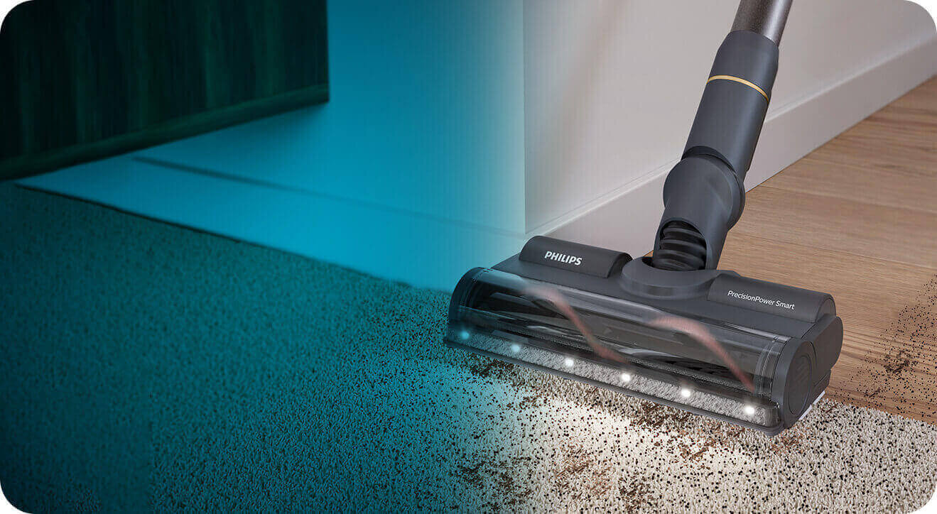 Odkurzacz z logo PHILIPS i napisem \'PowerCyclone 8\' odkurza brud z dywanu na podłogę. Urządzenie jest wyposażone w podświetlenie LED na szczotce.