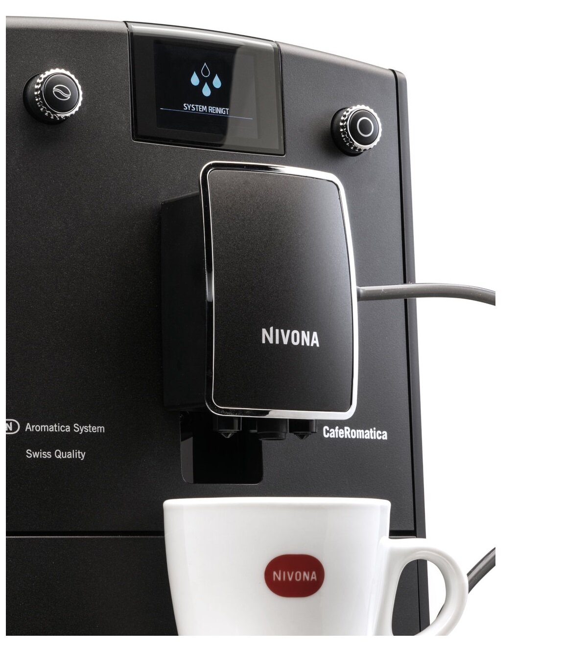 Na obrazie widoczny jest ekspres do kawy z wyświetlaczem pokazującym ikonę kropli i napis \'SYSTEM REINIGT\'. Na ekspresie znajduje się logo \'NIVONA\', a poniżej widoczna jest filiżanka z tym samym logo.