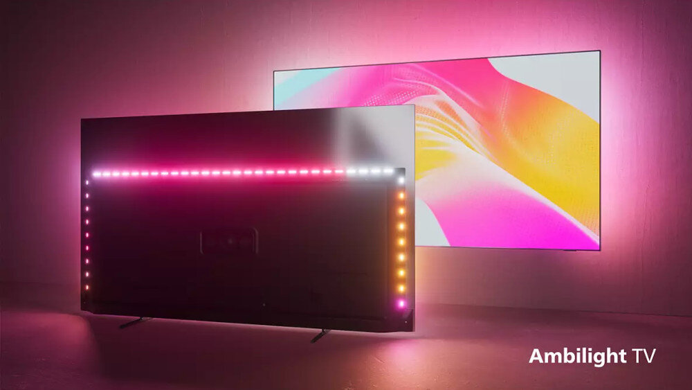 Telewizor z włączonym podświetleniem Ambilight, emitującym kolorowe światło na ścianę. W prawym dolnym rogu widoczny jest napis \'Ambilight TV\'.
