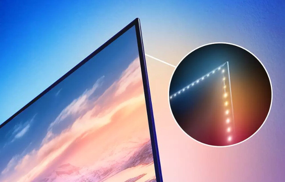 Obraz przedstawia zbliżenie na krawędź telewizora z widocznym efektem świetlnym Ambilight. W okrągłym powiększeniu pokazano szczegóły oświetlenia LED na krawędzi ekranu.