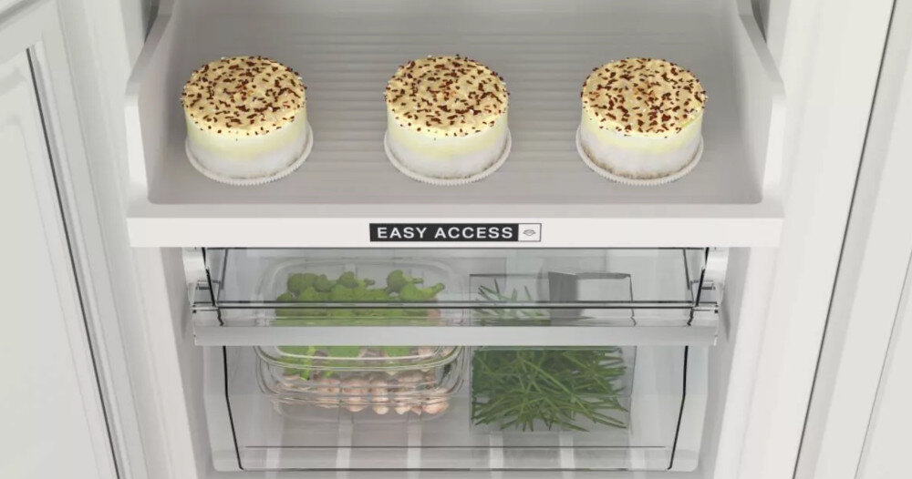 Wnętrze lodówki z trzema deserami na górnej półce i warzywami w dolnej szufladzie. Na półce widoczny jest napis \'EASY ACCESS\'.