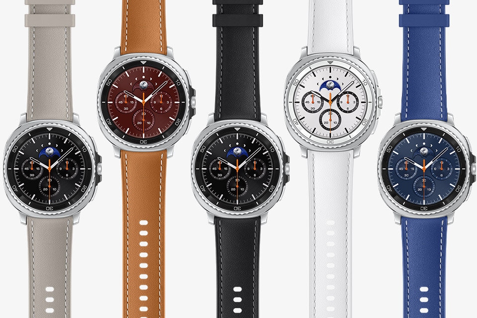 Pięć smartwatchy z okrągłymi tarczami, każdy z innym kolorem paska: szary, brązowy, czarny, biały i niebieski. Tarcze zegarków mają różne kolory i widoczne są na nich wskaźniki oraz symbol księżyca.