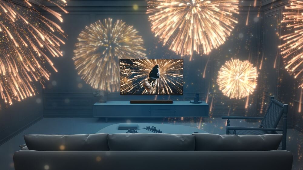 Pokój z sofą, telewizorem i soundbarem, na ekranie wyświetlane są fajerwerki. W tle widoczne są projekcje fajerwerków na ścianach.