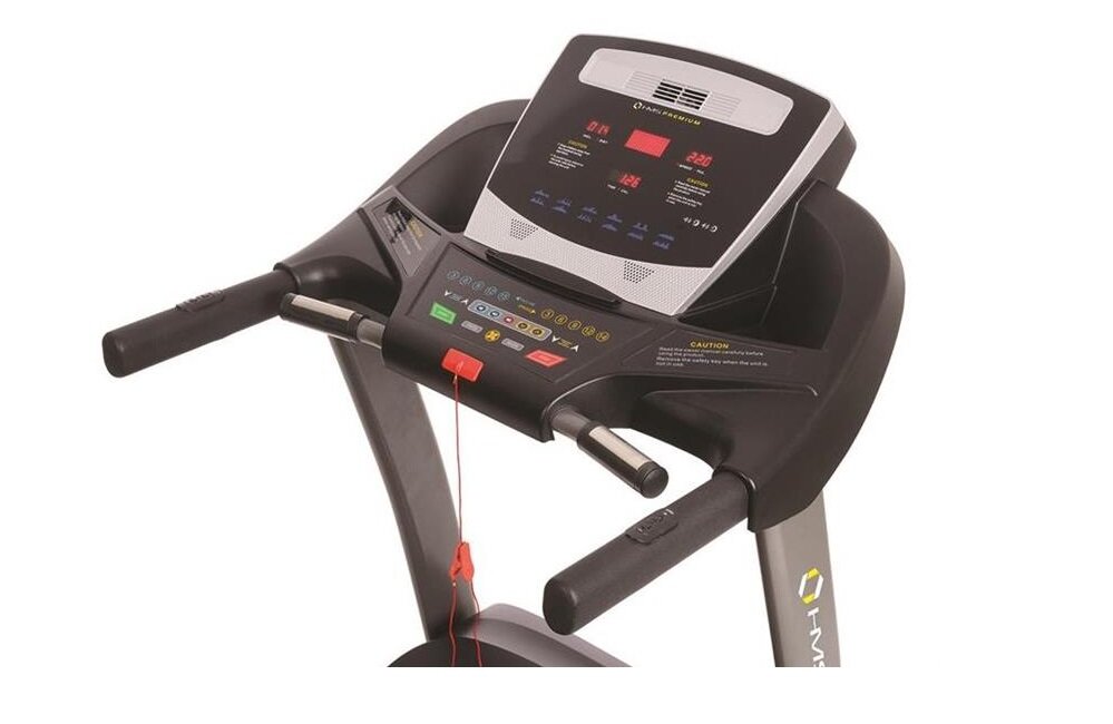 Na zdjęciu znajduje się panel sterowania bieżni elektrycznej z wyświetlaczem i przyciskami funkcyjnymi. Widoczne jest logo \'HMS\' oraz różnokolorowe przyciski i wskaźniki na czarnym tle.