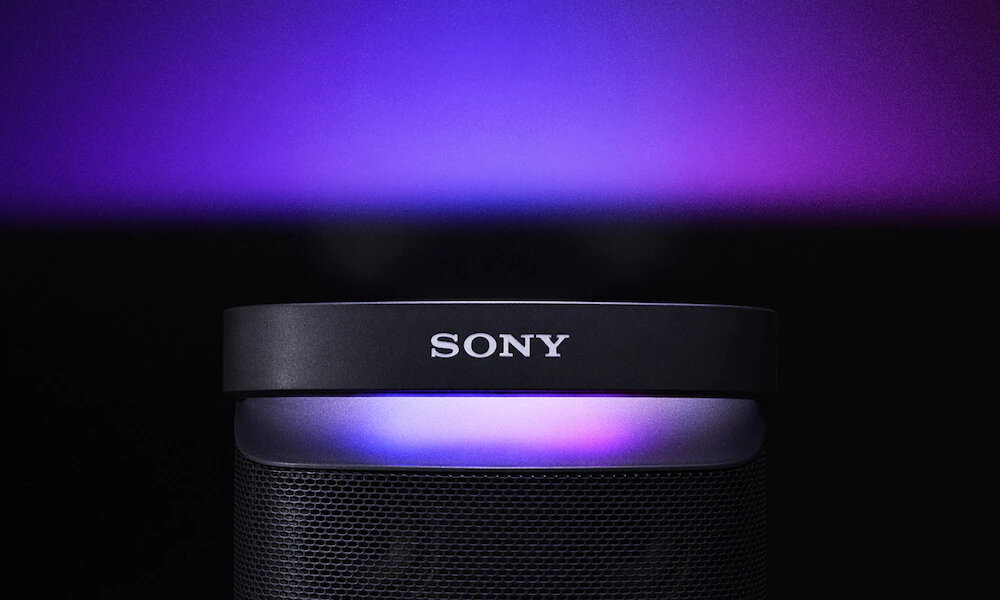 Głośnik z widocznym logo \'SONY\' na górnej części, z podświetleniem w odcieniach fioletu i niebieskiego. Tło jest ciemne, co podkreśla efekt świetlny urządzenia.