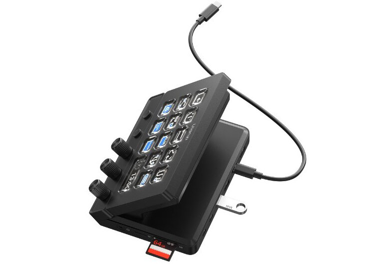 Na obrazie widoczny jest czarny panel z kilkoma pokrętłami i przyciskami, podłączony do urządzenia za pomocą kabla USB-C. W dolnej części panelu znajduje się gniazdo na kartę pamięci z włożoną kartą 64 GB.