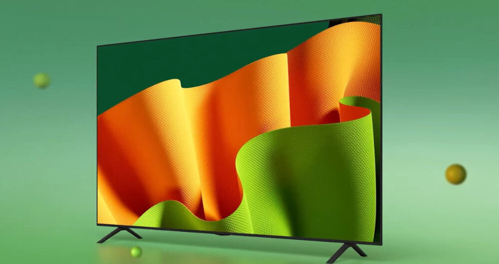 Telewizor z cienką ramką wyświetla kolorowy obraz z pomarańczowymi i zielonymi falami na zielonym tle. W tle widoczne są unoszące się kule w różnych odcieniach zieleni i żółci.