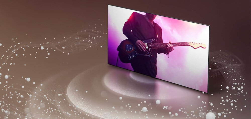 Telewizor wyświetla obraz osoby grającej na gitarze elektrycznej w różowym świetle. W tle widoczne są abstrakcyjne wzory przypominające fale dźwiękowe.