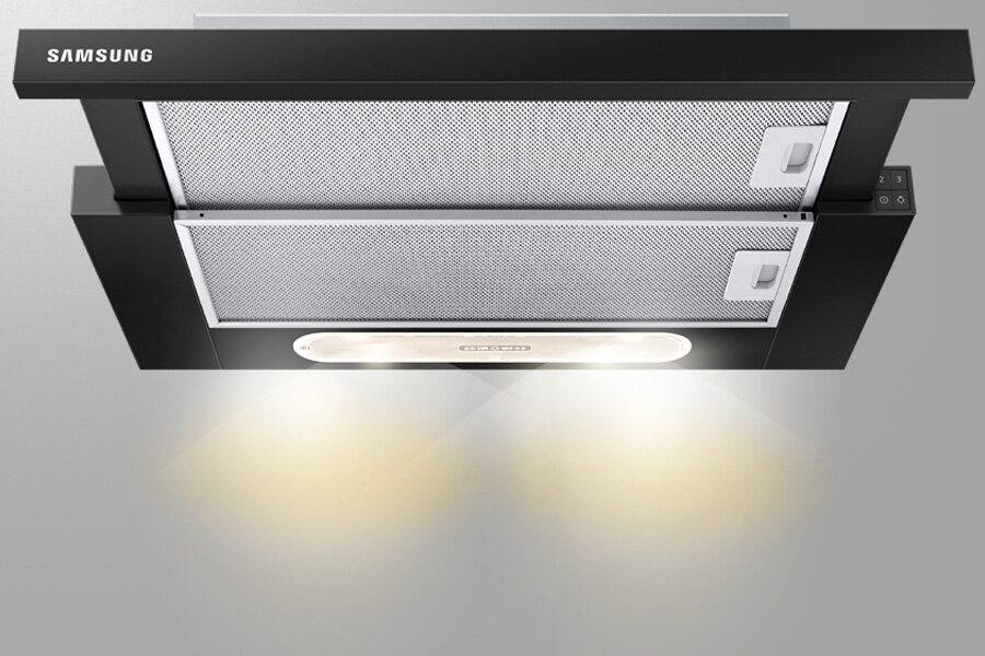 Czarny okap kuchenny z widocznymi dwoma metalowymi filtrami i podświetleniem. Na okapie znajduje się logo \'SAMSUNG\'.