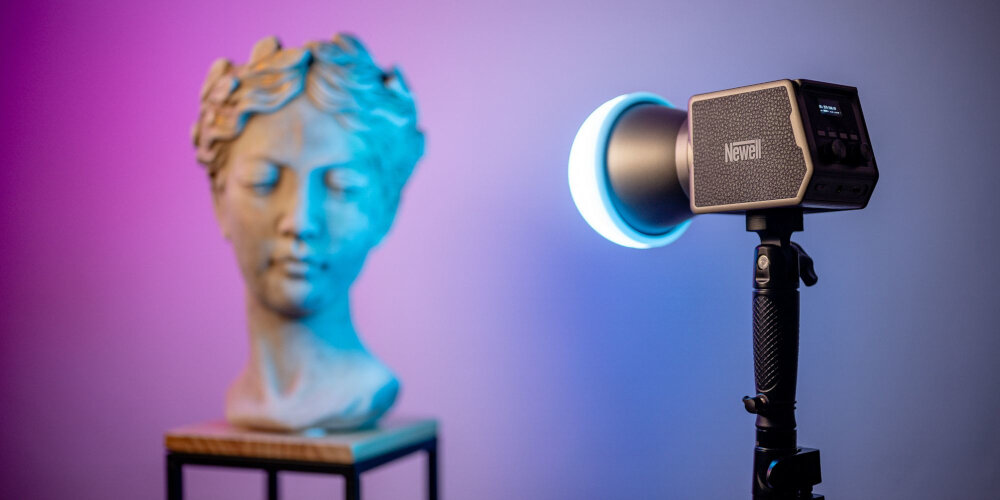 Lampa LED Newell z zamontowaną czaszą świeci niebieskim światłem, ustawiona na uchwycie obok gipsowego popiersia