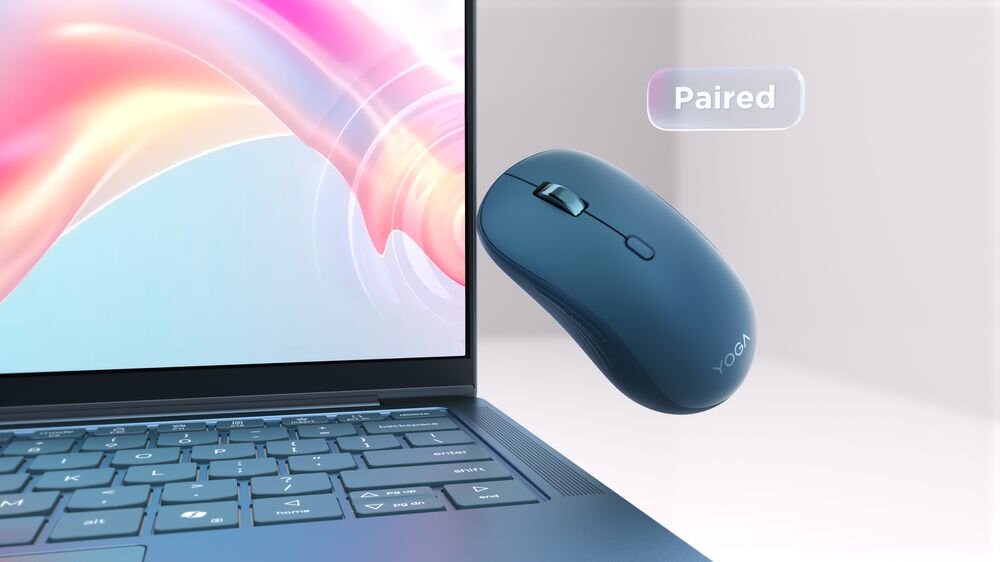 Niebieska mysz z napisem \'YOGA\' unosi się obok laptopa, na ekranie którego widoczny jest kolorowy wzór. Obok myszy znajduje się napis \'Paired\'.