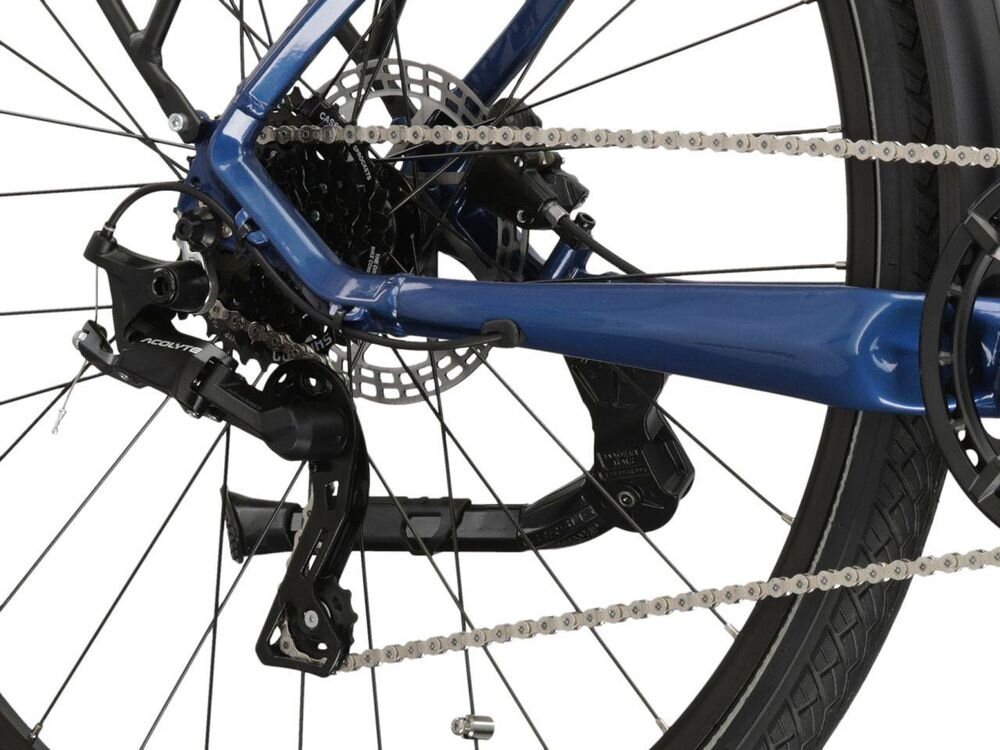 Zbliżenie na tylną część roweru z widocznym mechanizmem przerzutki i łańcuchem. Rama roweru jest w kolorze niebieskim, a opona czarna.