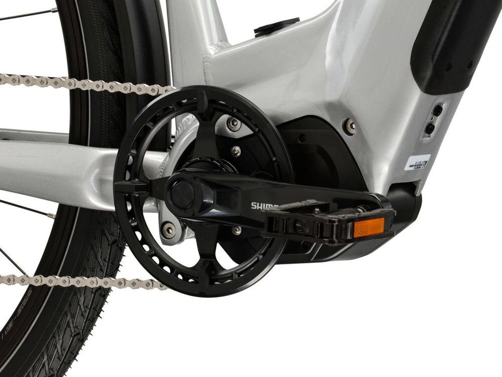 Zbliżenie na mechanizm napędowy roweru elektrycznego z widocznym pedałem i łańcuchem. Na korbie znajduje się napis \'SHIMANO\'.