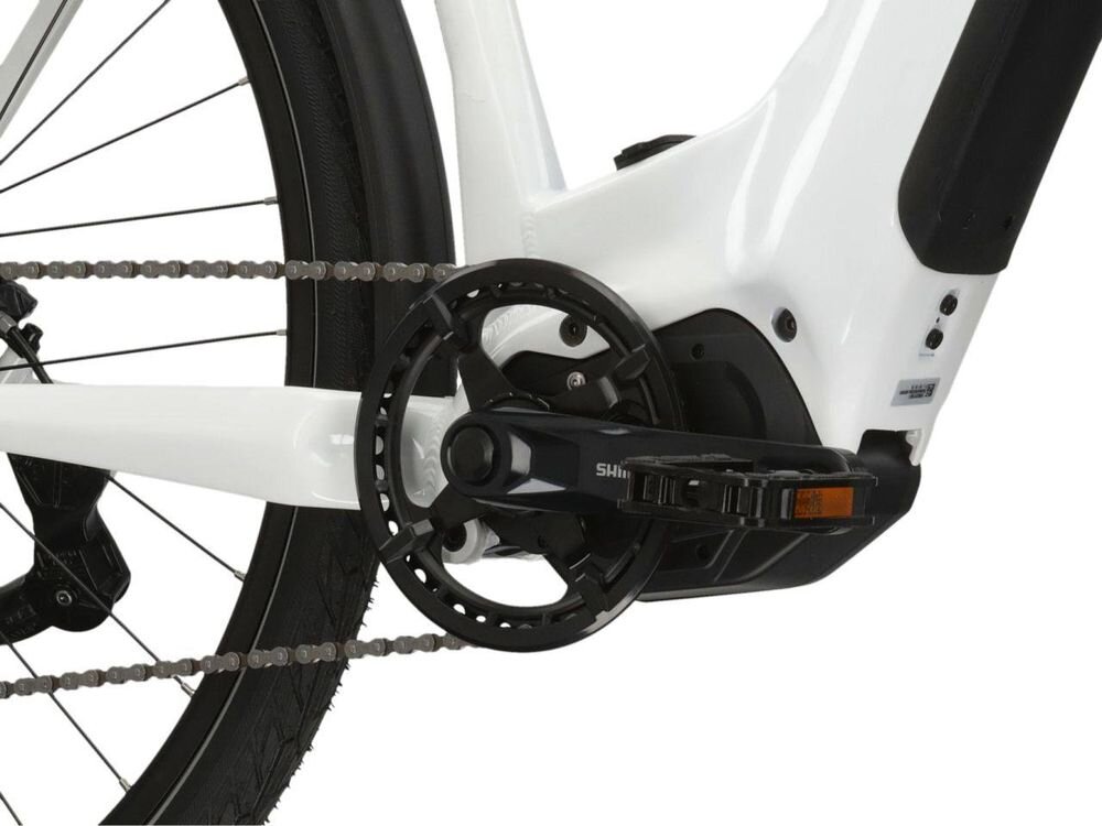 Zbliżenie na mechanizm napędowy roweru elektrycznego z widocznym pedałem i łańcuchem. Na elemencie napędu widoczny jest napis \'SHIMANO\'.