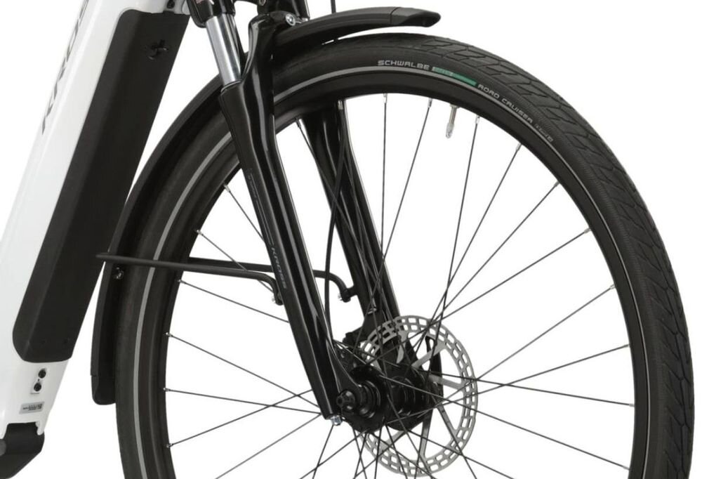 Zbliżenie na przednie koło roweru z widocznym amortyzatorem i tarczą hamulcową. Na oponie widoczny jest napis \'SCHWALBE ROAD CRUISER\'.