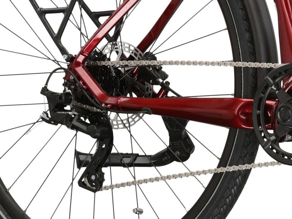 Zbliżenie na tylną część roweru z widocznym mechanizmem przerzutki, łańcuchem i tarczą hamulcową. Rama roweru jest w kolorze rubinowym.