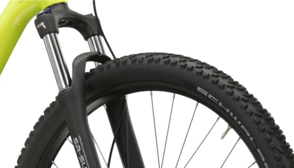 Rower górski MTB KROSS Level 1.0 M22 29 cali męski Limonkowo-czarny mat zbliżenie na amortyzator widok pod skosem białe tło rower typu hardtail przedni amortyzator marki SR Suntour typu XCT30 HLO skutecznie tłumi drgania i wstrząsy płynna i stabilna jazda amortyzator poprawia przyczepność kół kontrola nad rowerem wyższy poziom bezpieczeństwa i komfortu jazdy
