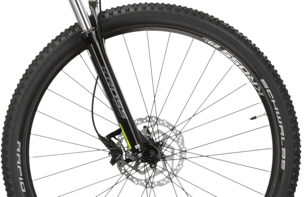 Zbliżenie na przednie koło roweru górskiego z widocznym amortyzatorem i tarczą hamulcową. Na oponie widoczny jest napis \'SCHWALBE RAPID\', a na widelcu \'KROSS\'.