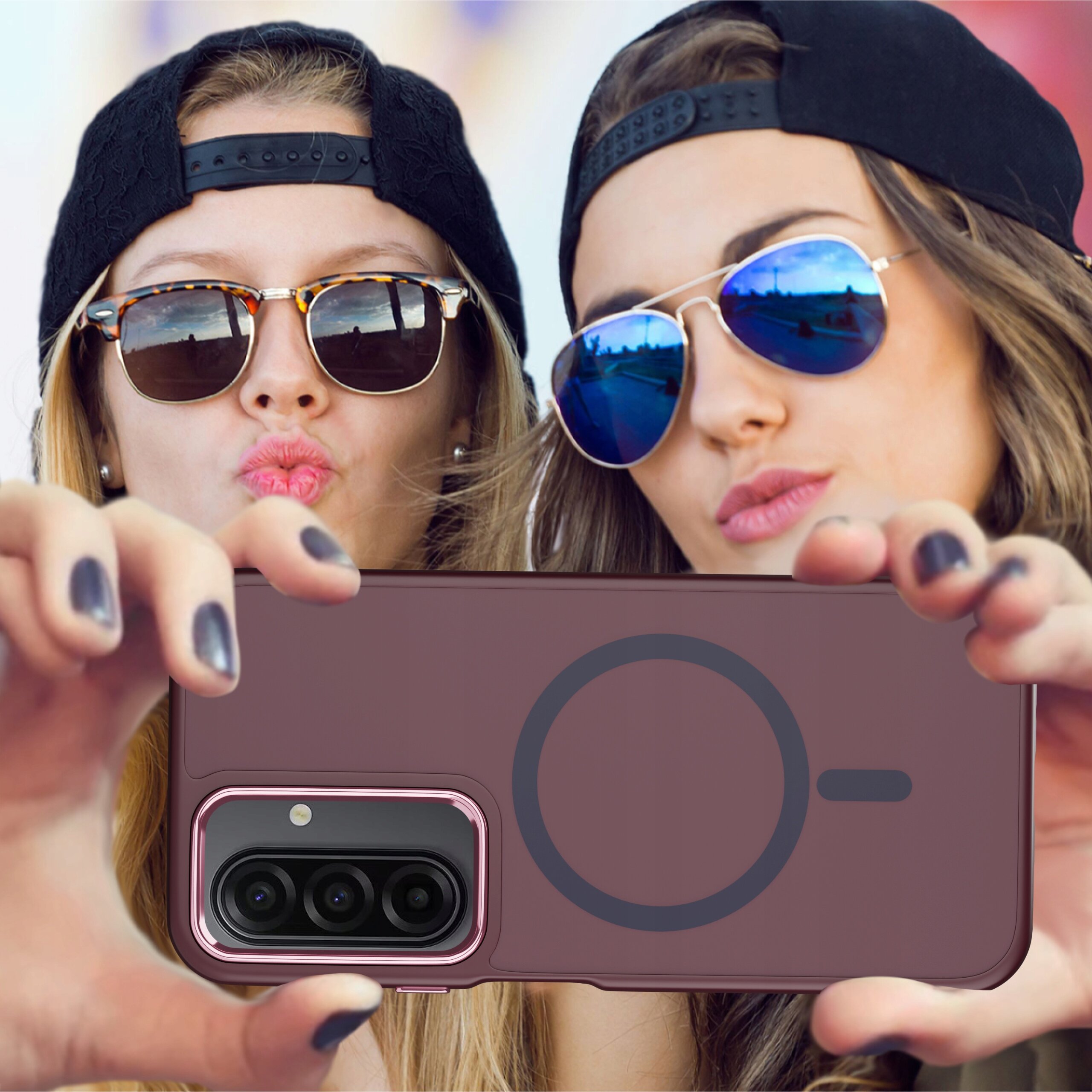 Dwie osoby w okularach przeciwsłonecznych trzymają telefon w etui z widocznym okrągłym wzorem na tylnej części. Etui jest matowe i ma wycięcie na aparat z trzema obiektywami.
