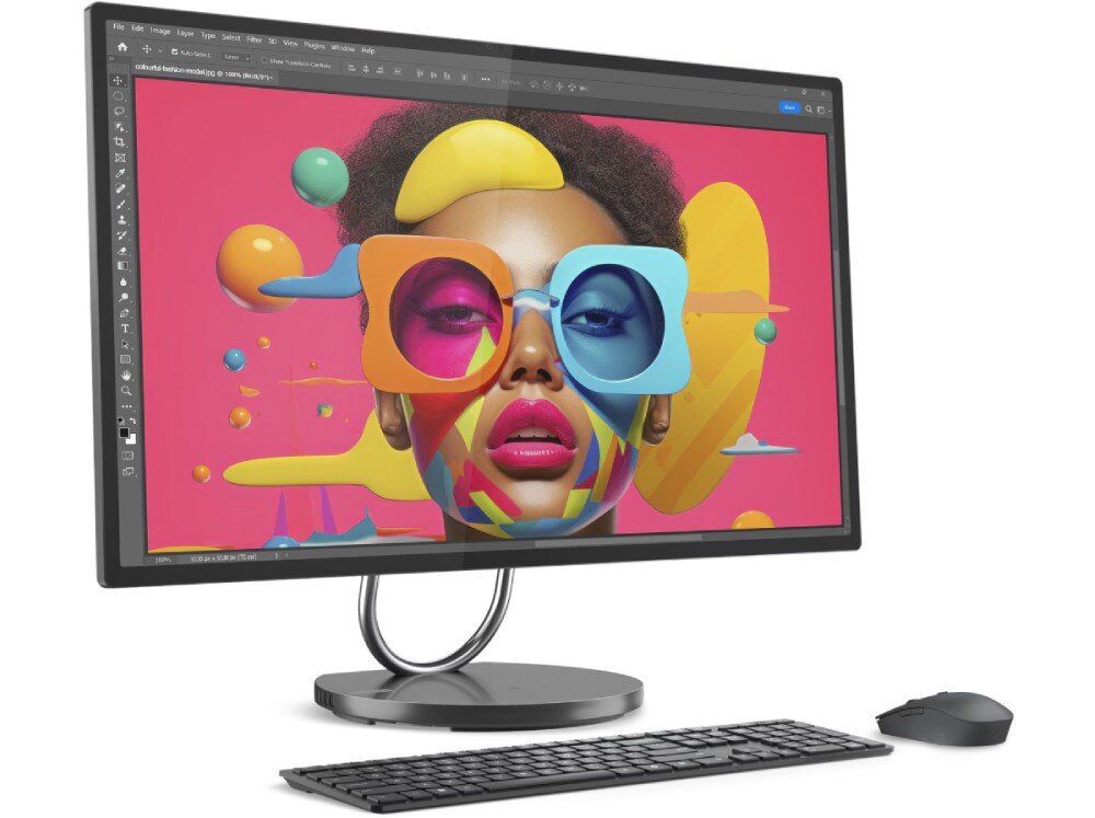 Komputer All in One z dużym monitorem wyświetlającym kolorową grafikę twarzy w okularach. Przed monitorem znajduje się klawiatura i myszka.