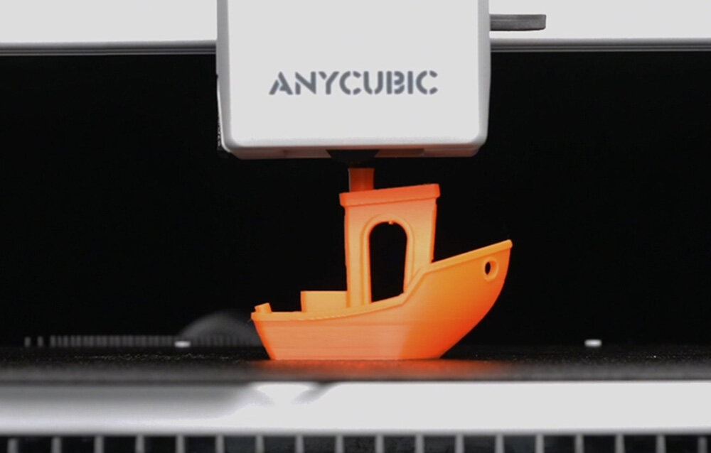 Drukarka 3D ANYCUBIC Kobra X Drukarka 3D drukująca pomarańczowy model łódki na platformie roboczej