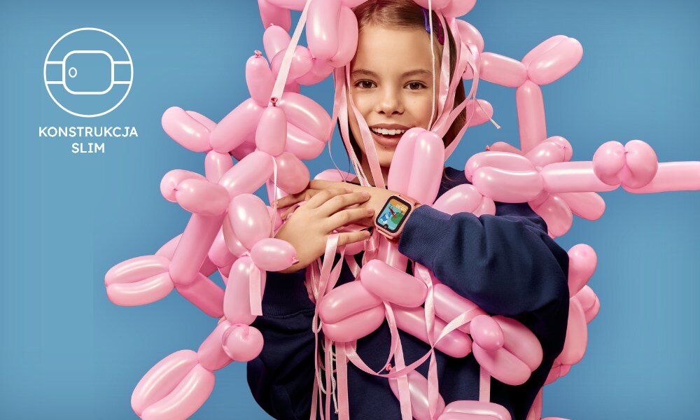 Osoba otoczona różowymi balonami nosi smartwatch na nadgarstku. Obok znajduje się symbol zegarka z napisem \'KONSTRUKCJA SLIM\'.