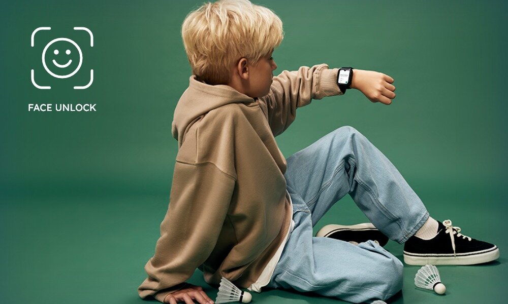 Osoba siedzi na podłodze w jasnej bluzie i dżinsach, patrząc na smartwatch na nadgarstku. Obok widoczne są lotki do badmintona, a w rogu znajduje się ikona z napisem \'FACE UNLOCK\'.