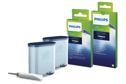 Na obrazie znajdują się dwa pojemniki z niebieskimi pokrywkami oraz dwie zielone pudełka z napisami \'PHILIPS Milk Circuit Cleaner\' i \'PHILIPS Coffee oil remover\'. Obok pojemników leży biały pędzelek.