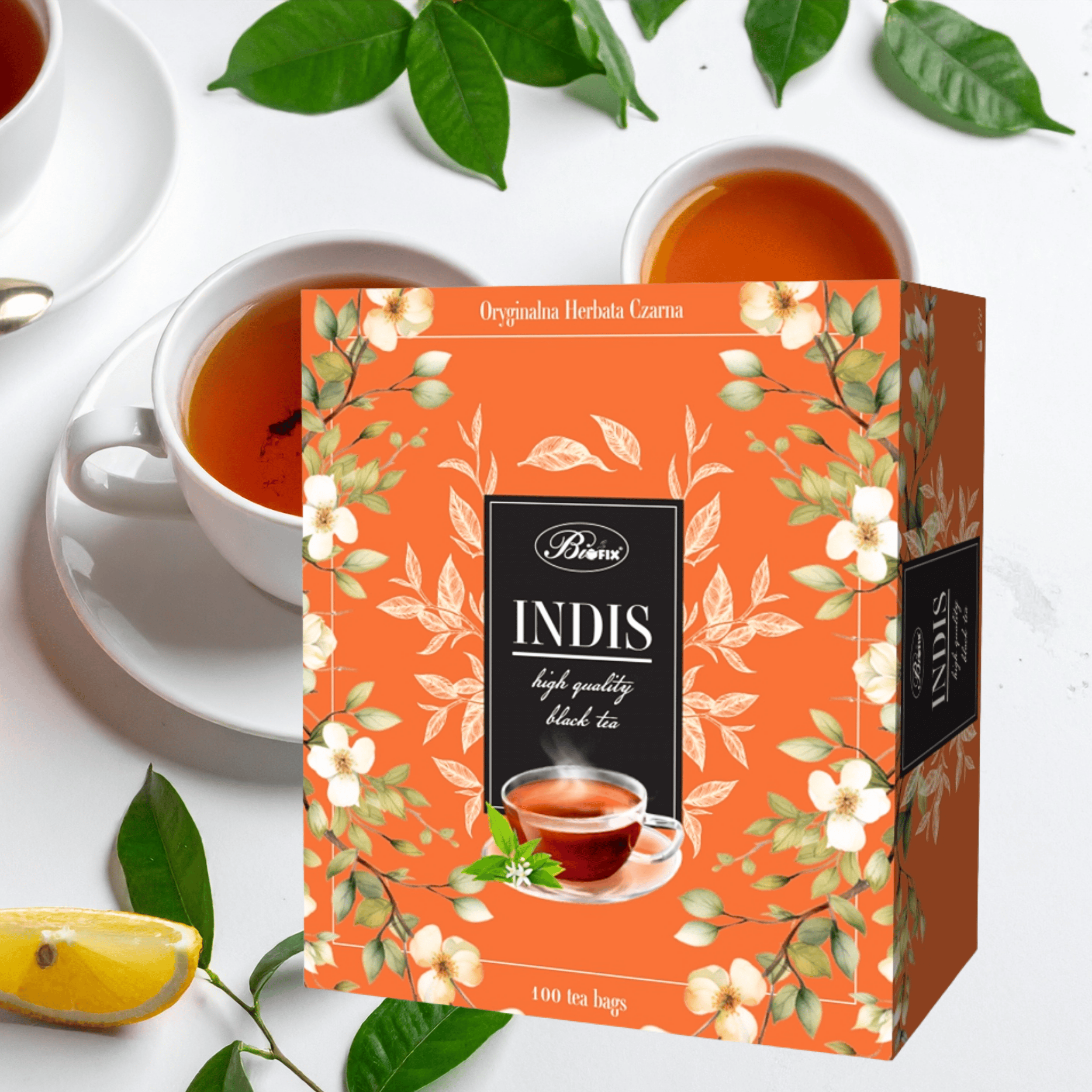 Opakowanie herbaty czarnej Bifix Indis z napisem \'Oryginalna Herbata Czarna\' i \'100 tea bags\' na pomarańczowym tle z kwiatowym wzorem. Obok znajdują się filiżanki z herbatą i plasterek cytryny.