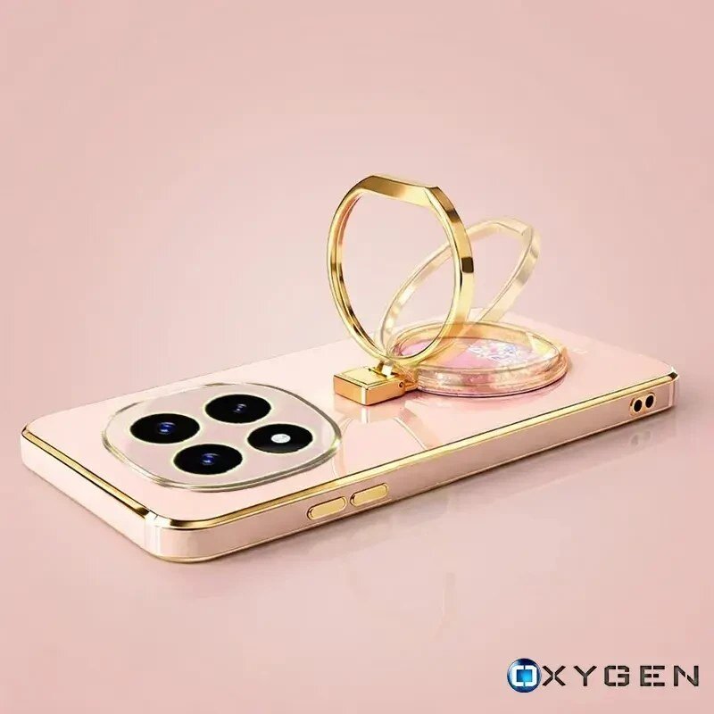 Na obrazie widoczne jest eleganckie etui na telefon w kolorze różowym z elementami złotymi, posiadające pierścień do trzymania. W prawym dolnym rogu znajduje się logo \'OXYGEN\'.