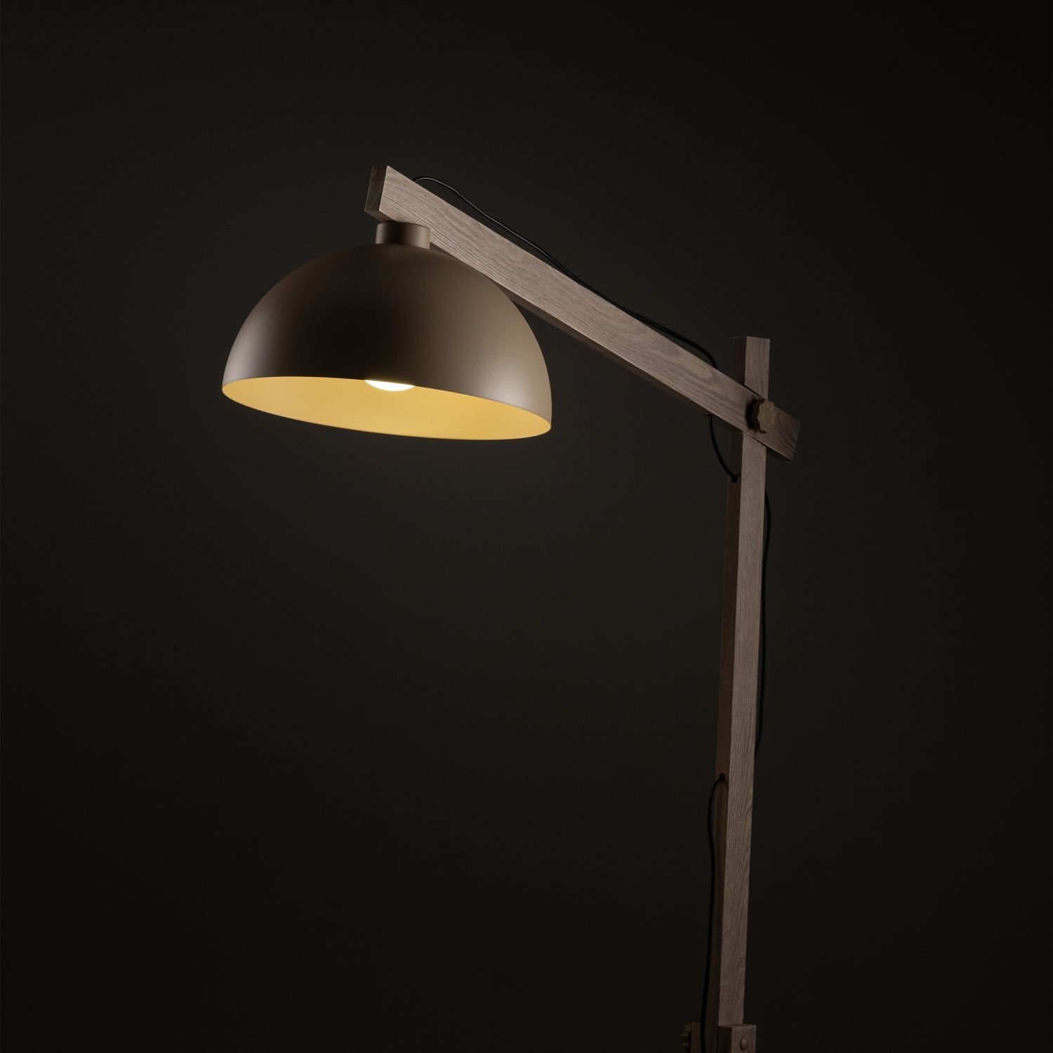 Lampa podłogowa z beżowym kloszem i drewnianym stelażem na ciemnym tle.