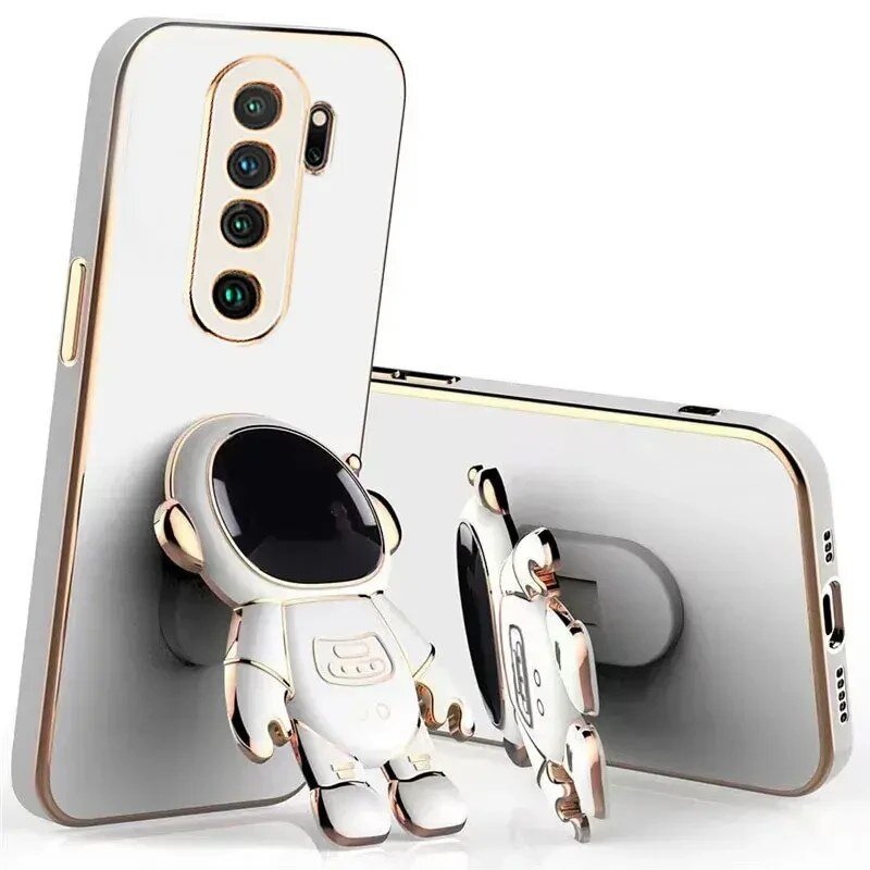 Na obrazie widoczne są dwa etui na telefon z motywem astronauty, jedno stojące, drugie leżące. Etui mają biały kolor z elementami złota i posiadają wycięcia na aparat oraz przyciski.