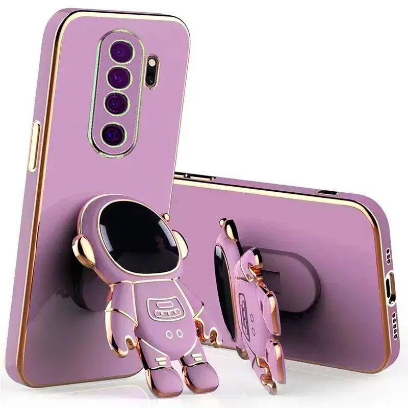 Na obrazie widoczne są dwa fioletowe etui na telefon z motywem astronauty, z wycięciami na aparat i przyciski. Etui posiadają ozdobne elementy w kolorze złotym.