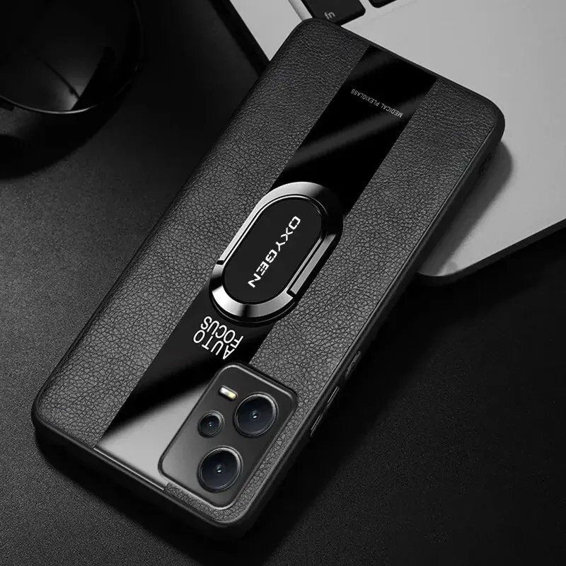 Na obrazie widoczne jest etui na telefon z napisem \'OXYGEN\' oraz \'AUTO FOCUS\'. Etui ma teksturę przypominającą skórę i jest umieszczone na ciemnym tle obok laptopa.