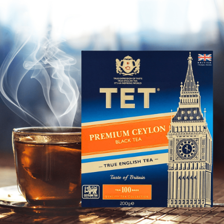Na obrazie znajduje się opakowanie herbaty TET Premium Ceylon Black Tea z grafiką przedstawiającą Big Ben oraz filiżanka z parującą herbatą. Na opakowaniu widnieje napis: \'PREMIUM CEYLON BLACK TEA - TRUE ENGLISH TEA - Taste of Britain - Tea 100 bags - 200g\'.
