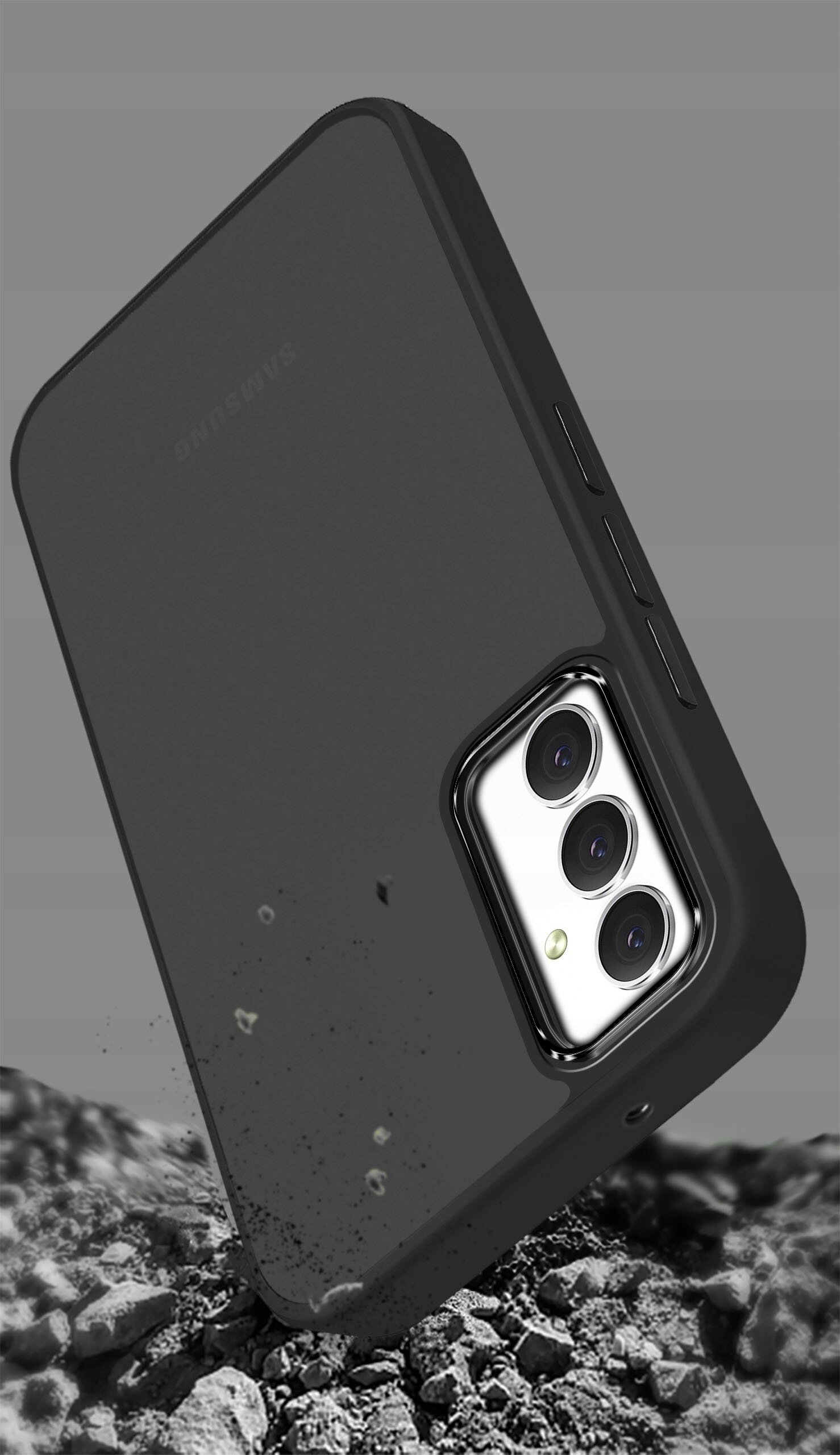 Czarne, matowe etui na telefon z trzema wycięciami na aparaty, leży na tle przypominającym kamienie. Na etui widoczne jest logo \'Samsung\'.