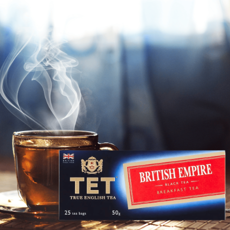 Na obrazie znajduje się filiżanka z parującą herbatą oraz opakowanie herbaty z napisem \'BRITISH EMPIRE BLACK TEA BREAKFAST TEA\'.
